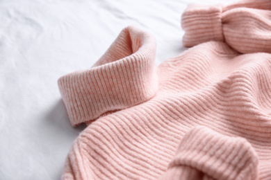 Photo of Pink warm sweater on white crumpled fabric, closeup