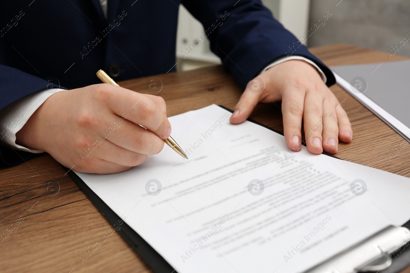 Photo of Man signing document at wooden table, closeup