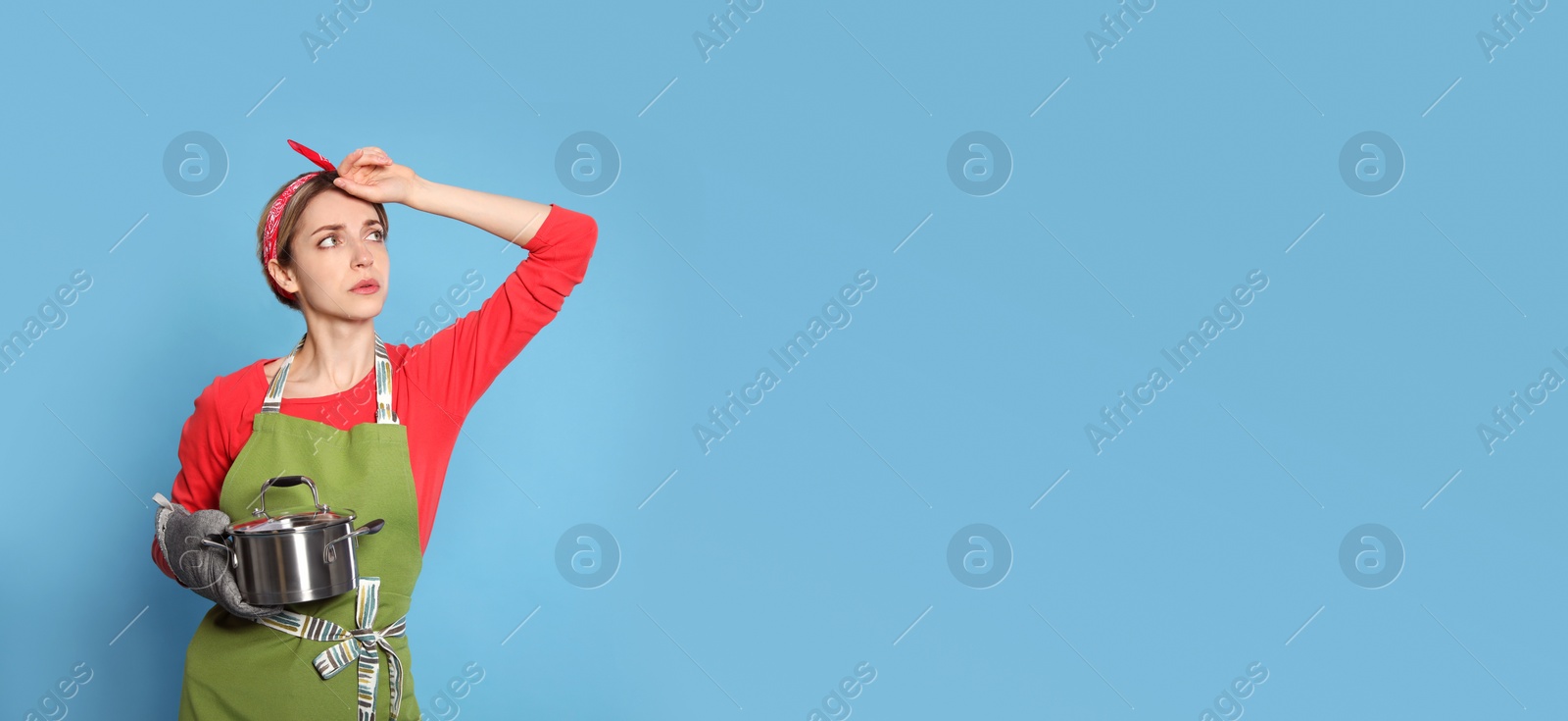 Photo of Young housewife with pot on light blue background. Space for text
