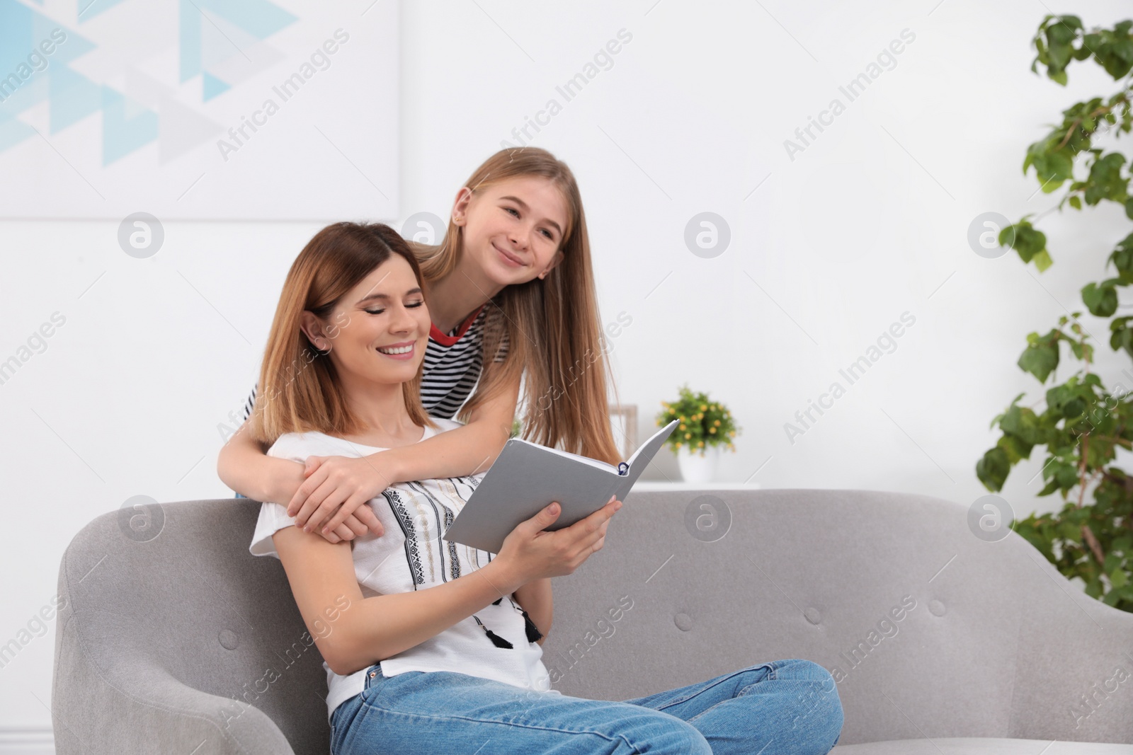 Photo of Happy mother and her teenage daughter with book at home