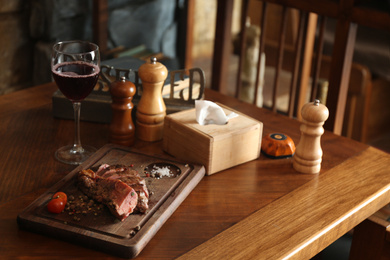 Photo of Tasty roasted meat served on wooden table in restaurant. Cooking food