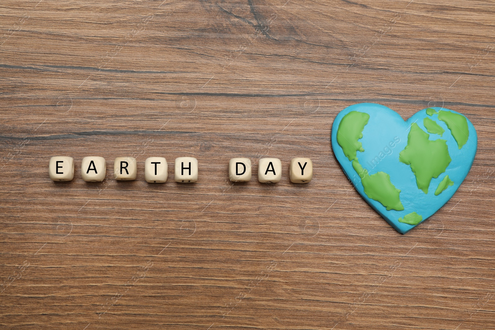Photo of Cubes with words Earth Day and heart shaped plasticine planet on wooden table, flat lay