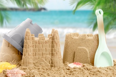 Image of Sand castles with toys on ocean beach, closeup. Outdoor play