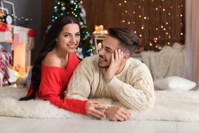 Photo of Happy young couple lying on floor at home. Christmas celebration