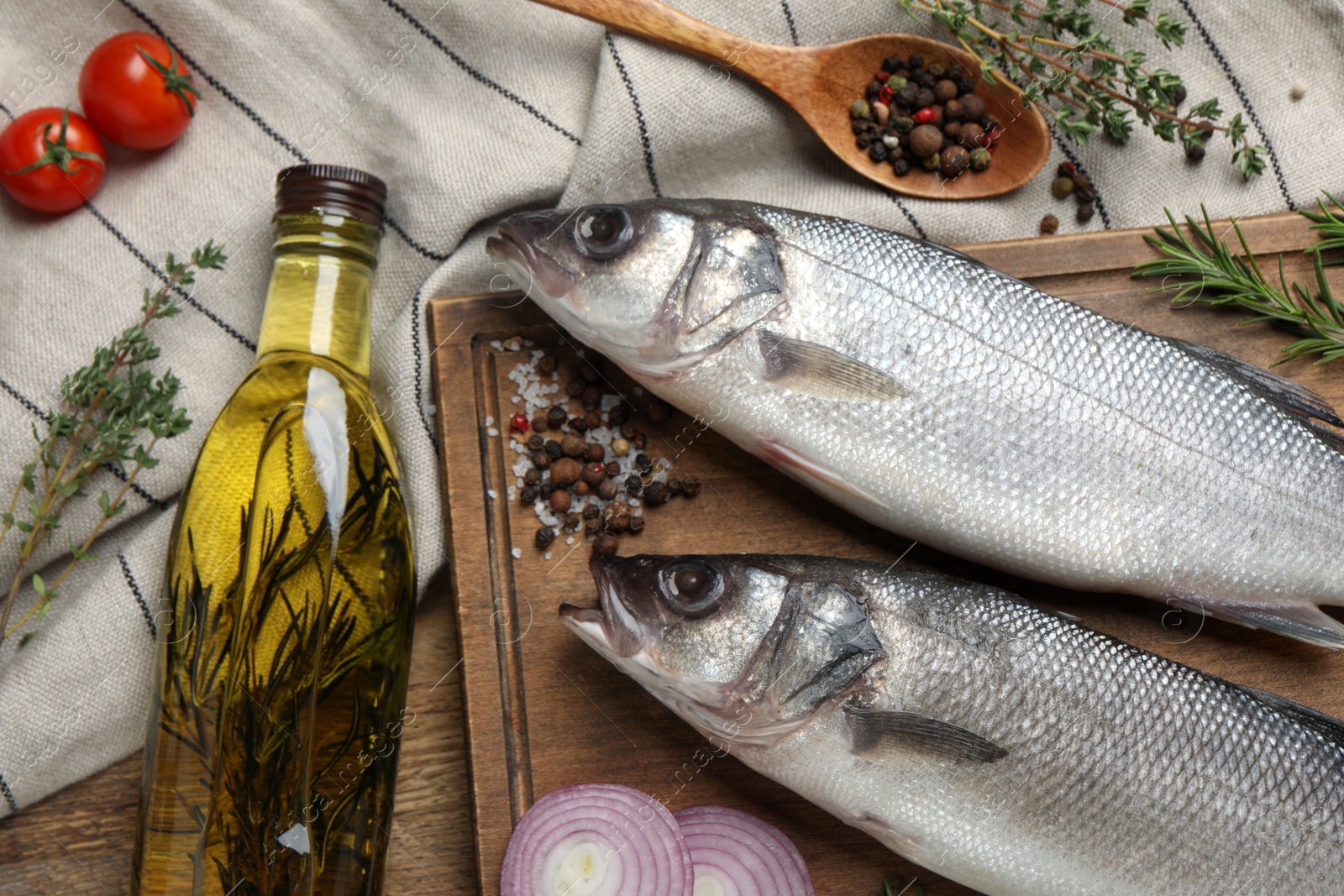 Photo of Sea bass fish and ingredients on wooden table, flat lay