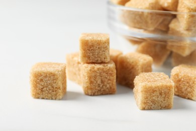 Photo of Brown sugar cubes on white table, closeup
