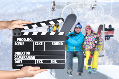 Image of Assistant holding clapperboard and people using chairlift at mountain ski resort, closeup. Cinema production 