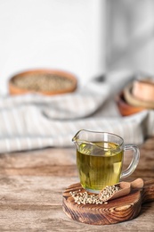 Jug with hemp oil and seeds on wooden table