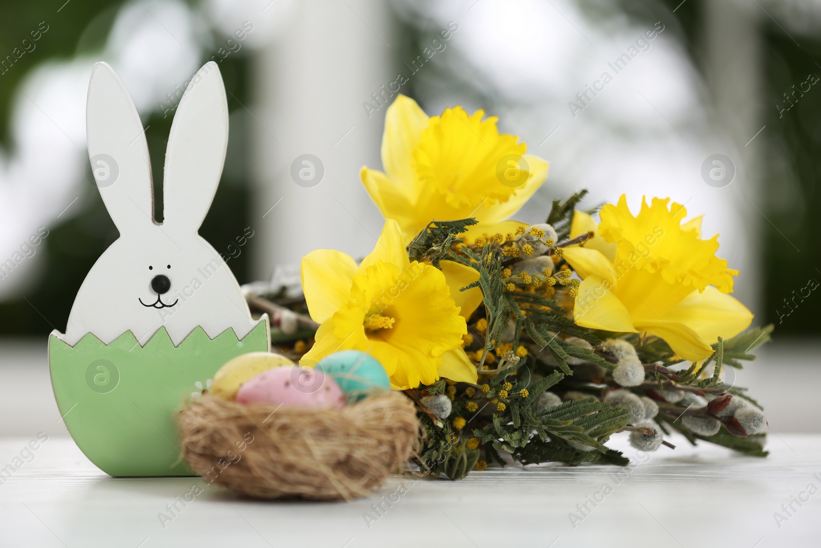 Photo of Festive composition with Easter eggs on table against blurred window