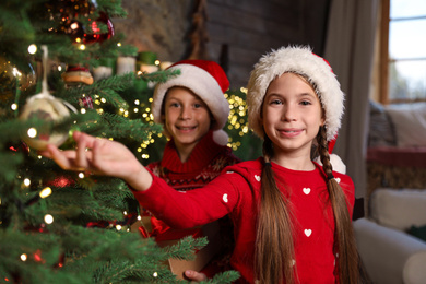 Happy children near beautiful Christmas tree at home