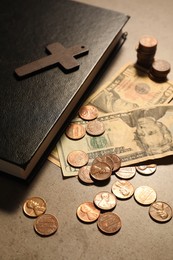 Donate and give concept. Coins, Bible, cross and dollar banknotes on grey table