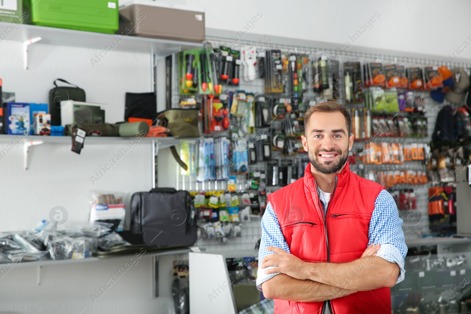 Photo of Salesman standing near showcase with fishing equipment in sports shop. Space for text