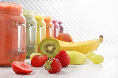 Photo of Many different tasty smoothies and ingredients on white wooden table, space for text