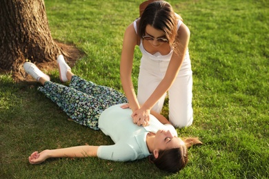 Photo of Woman doing cardiac massage to unconscious person with heart attack on green lawn