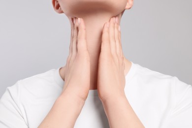 Photo of Woman with sore throat on light grey background, closeup