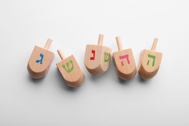 Photo of Wooden dreidels on white background, flat lay. Traditional Hanukkah game