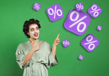 Discount offer. Happy woman in bathrobe pointing at falling cubes with percent signs on green background