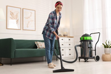 Photo of Young woman vacuuming floor in living room