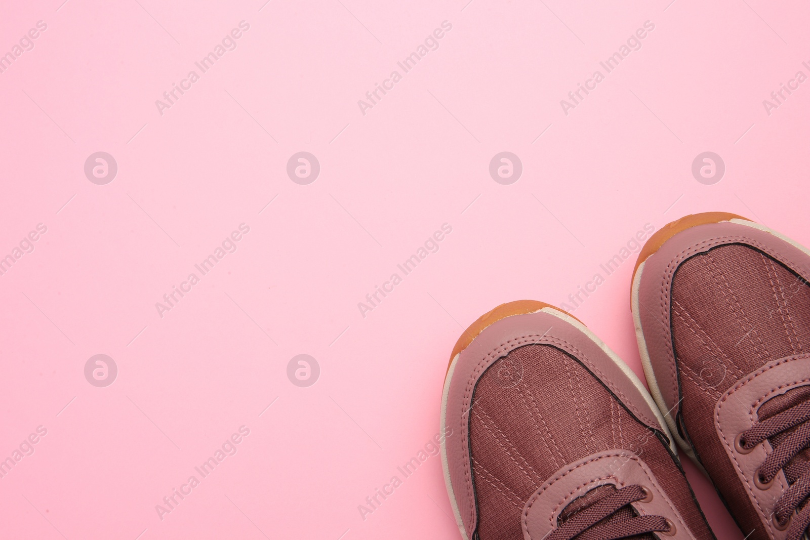 Photo of Pair of stylish kid's sneakers on pink background, top view. Space for text