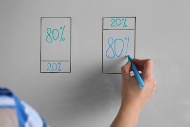 Photo of Woman writing 80/20 rule representation on flip chart board, closeup. Pareto principle concept