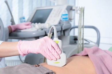 Photo of Doctor conducting ultrasound examination of patient's abdomen in clinic, closeup