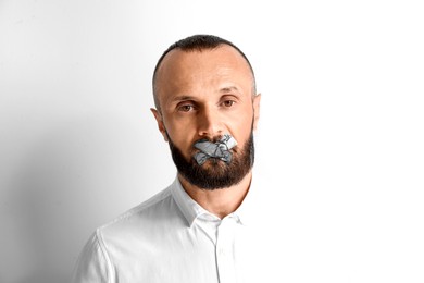 Mature man with taped mouth on white background. Speech censorship