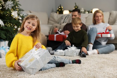 Family Christmas celebration. Little girl with gift at home, selective focus