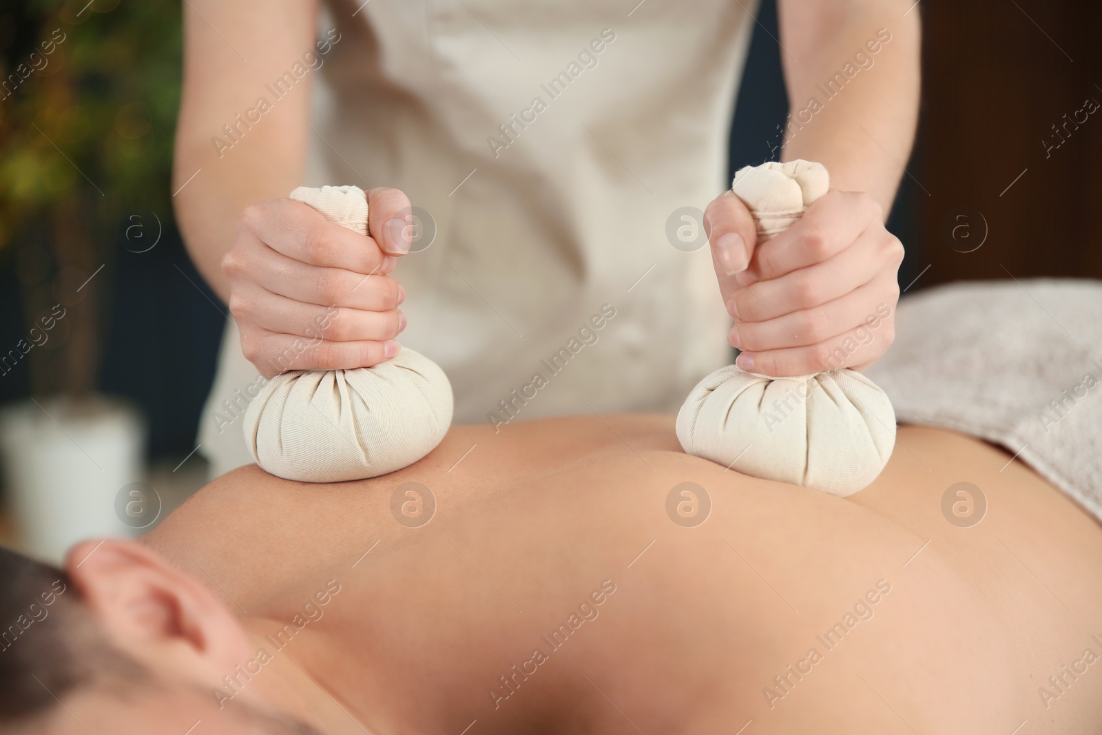 Photo of Man receiving herbal bag massage in spa salon, closeup