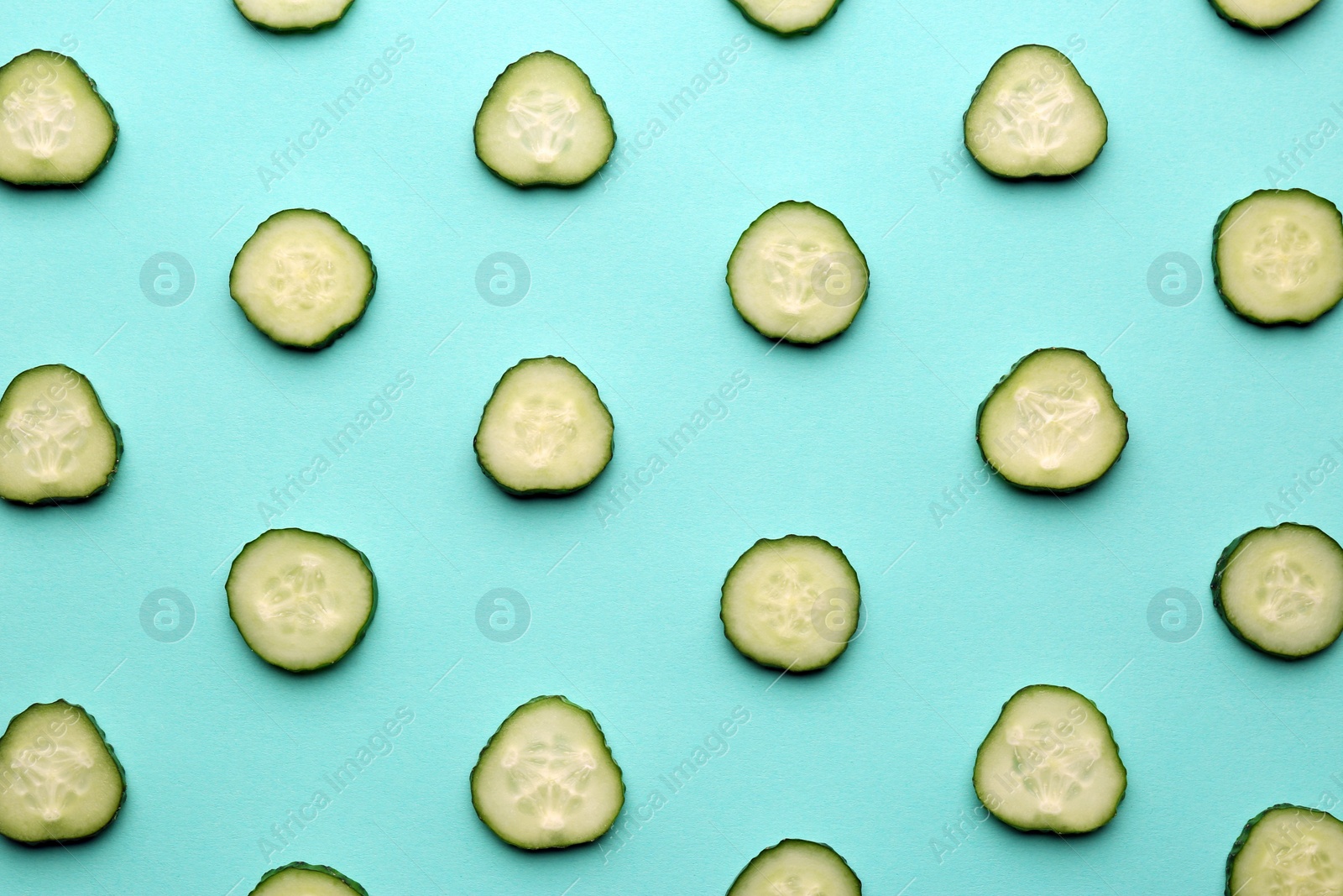 Photo of Slices of fresh ripe cucumber on turquoise background, flat lay