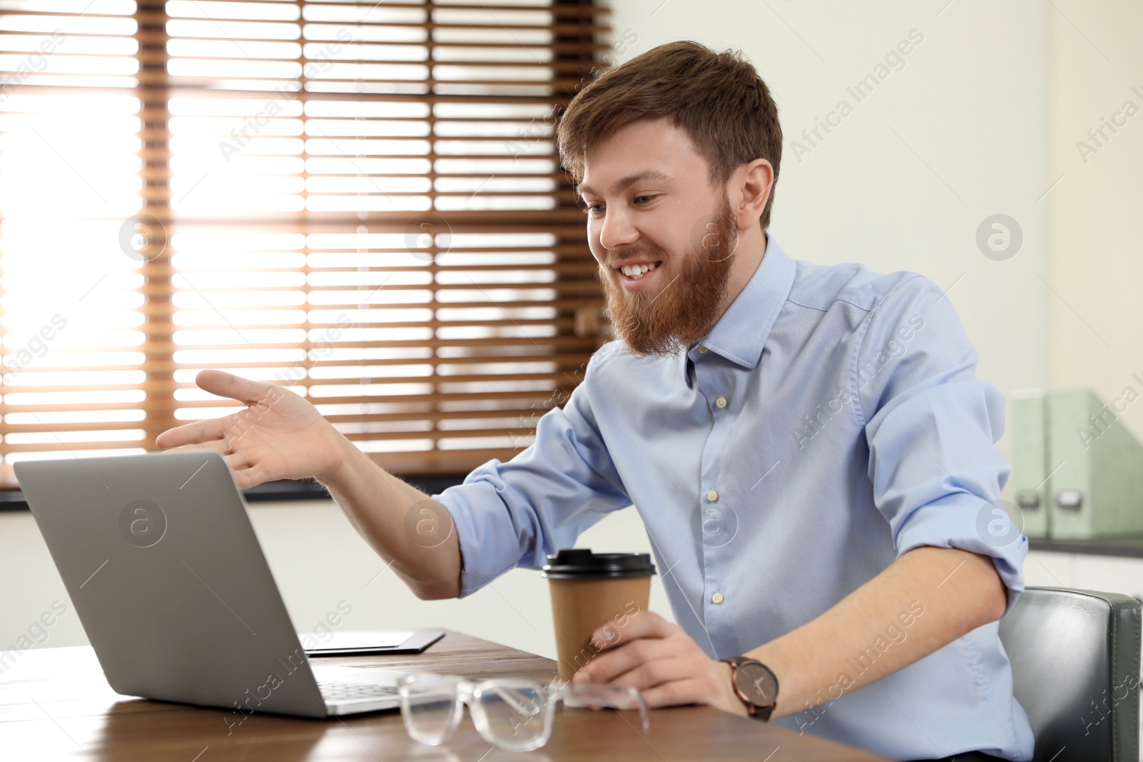 Photo of Man using video chat on laptop in home office
