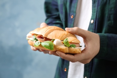Photo of Man holding tasty croissant sandwich, closeup