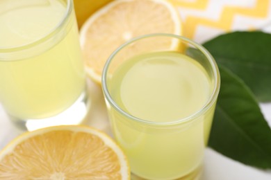 Photo of Tasty limoncello liqueur and lemons on table, closeup