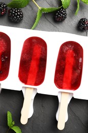 Photo of Tasty berry ice pops in mold on grey table, flat lay. Fruit popsicle