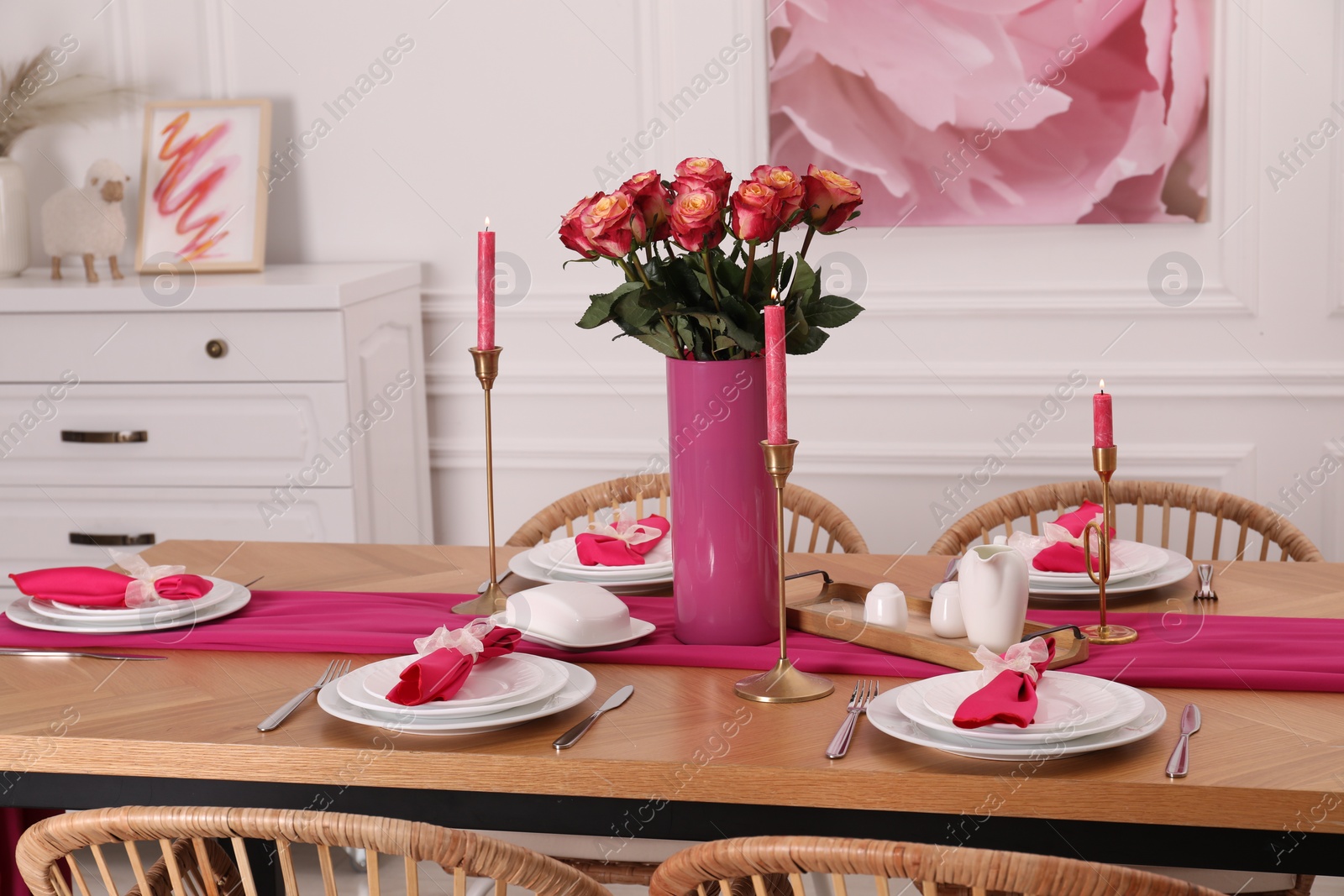 Photo of Color accent table setting. Plates, cutlery, pink napkins and vase with beautiful roses in dining room