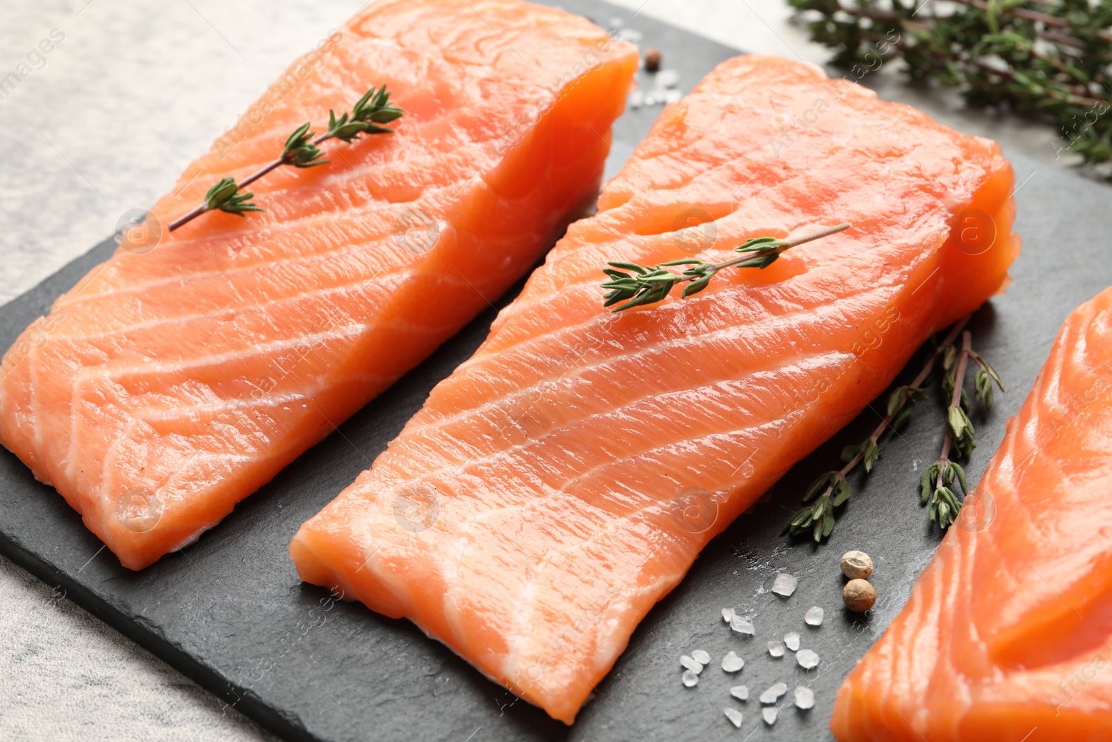 Photo of Fresh raw salmon and ingredients for marinade on slate board, closeup