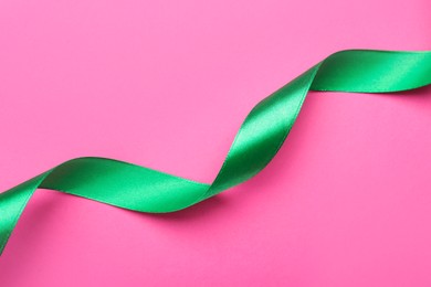 Photo of Beautiful ribbon on pink background, top view