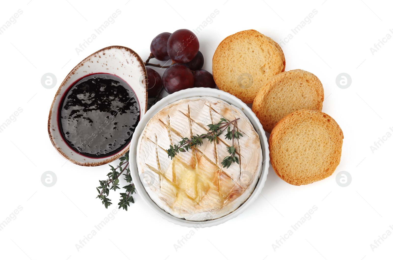 Photo of Tasty baked camembert, croutons, grapes and jam isolated on white, top view