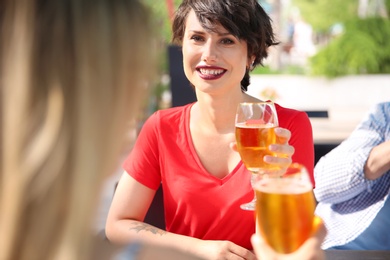 Young women with glasses of cold beer at table