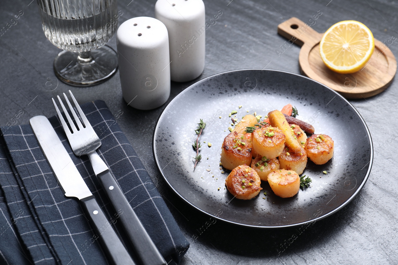 Photo of Delicious fried scallops served on dark gray textured table