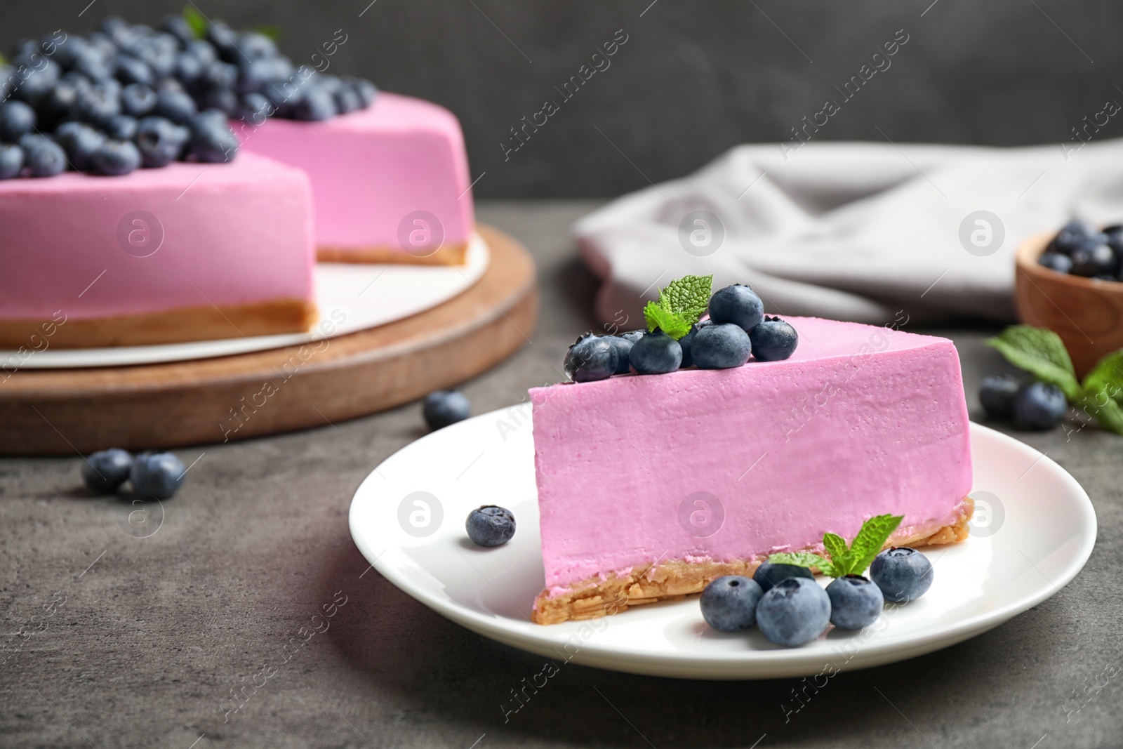 Photo of Plate with piece of tasty blueberry cake on grey table. Space for text