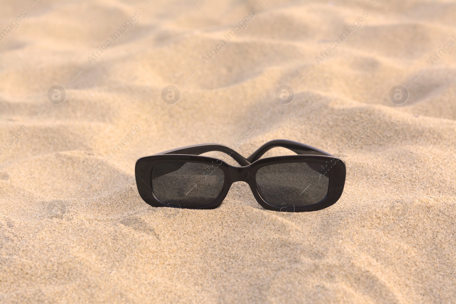 Photo of Stylish sunglasses on sandy beach, space for text