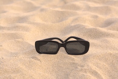 Stylish sunglasses on sandy beach, space for text