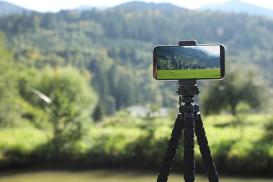 Photo of Taking photo of beautiful mountain landscape with smartphone mounted on tripod outdoors