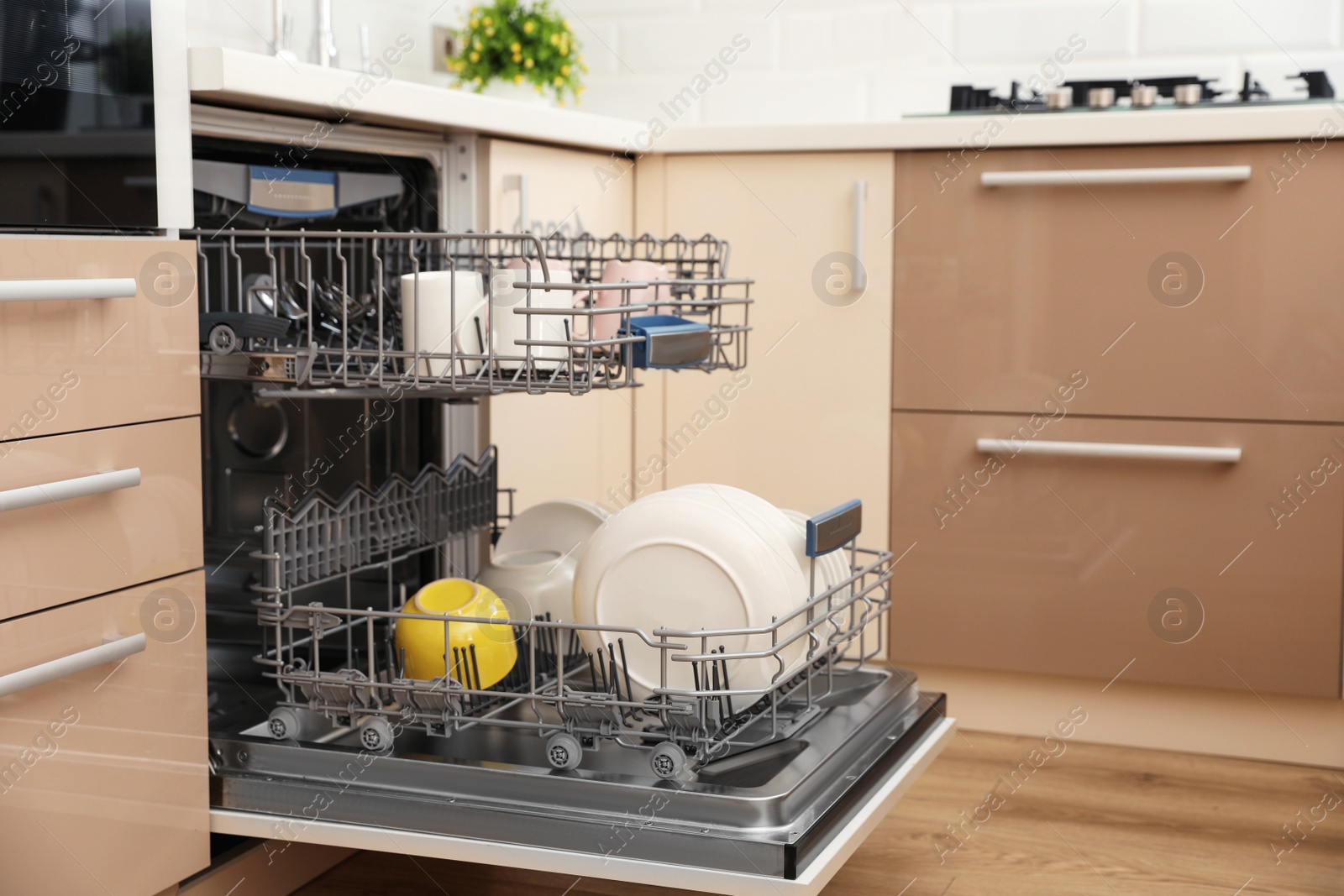 Photo of Open dishwasher with clean tableware in kitchen. Space for text