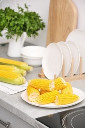 Photo of Plate with ripe corn cobs on kitchen table