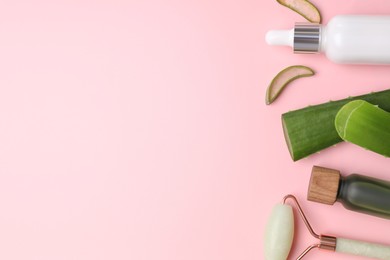 Photo of Cosmetic products, cut aloe leaves and face roller on pink background, flat lay. Space for text