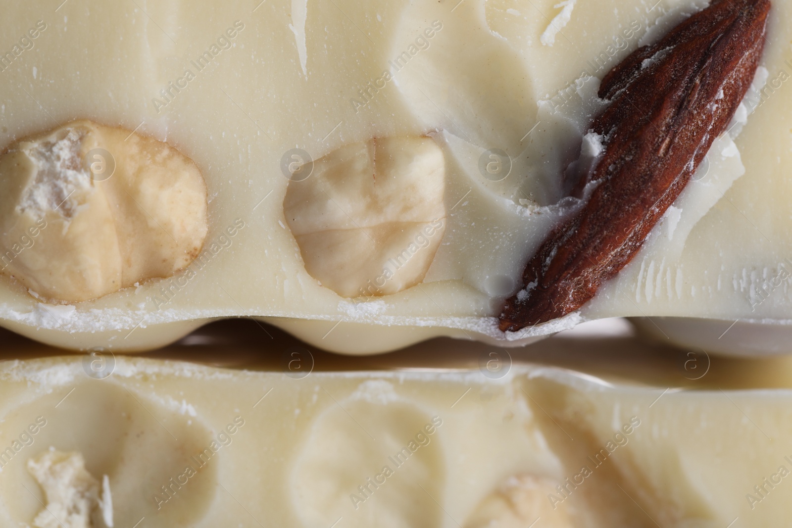 Photo of Pieces of tasty white chocolate with nuts as background, closeup