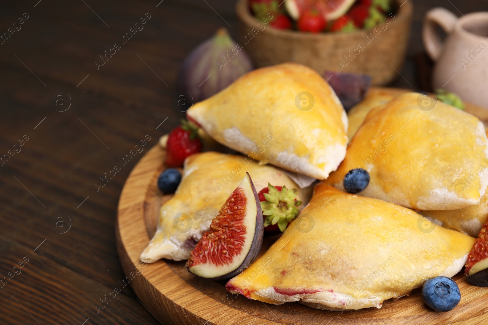 Photo of Delicious samosas with figs and berries on wooden table, closeup. Space for text