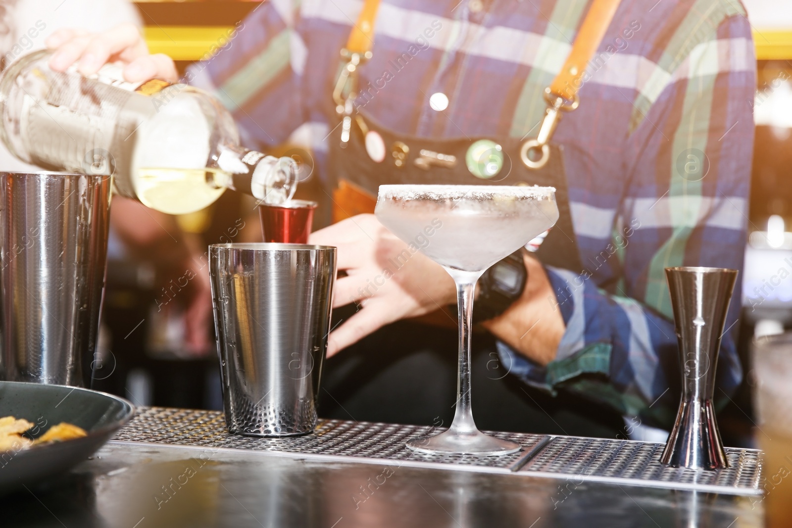 Photo of Bartender preparing tasty cocktail at counter in nightclub, closeup