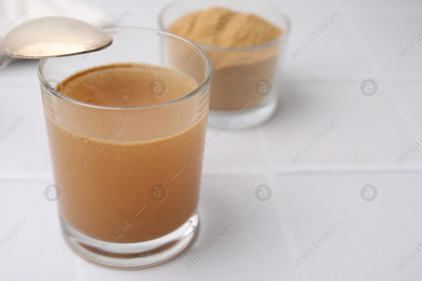 Photo of Soluble fiber with water in glass and powder on white tiled table, closeup. Space for text